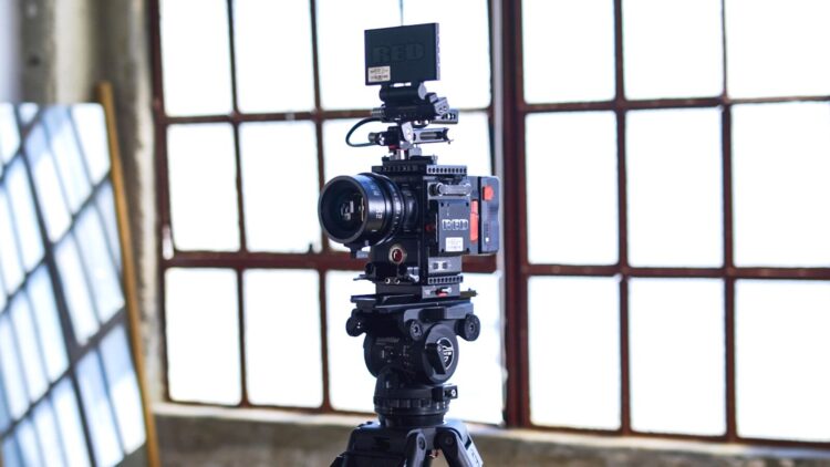 black filming camera on tripod near window