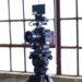 black filming camera on tripod near window