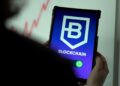 a person holding a cell phone with a blockchain logo on it