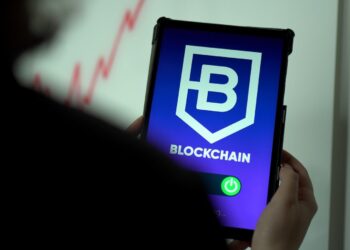 a person holding a cell phone with a blockchain logo on it