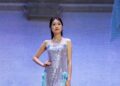 A woman in a sequined dress walks on a stage.