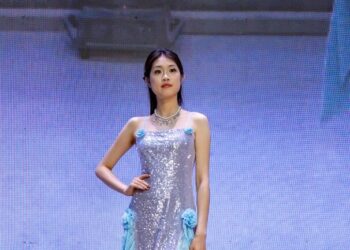 A woman in a sequined dress walks on a stage.