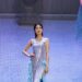 A woman in a sequined dress walks on a stage.